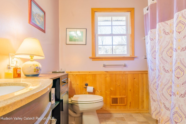 full bath with vanity, wooden walls, visible vents, wainscoting, and toilet