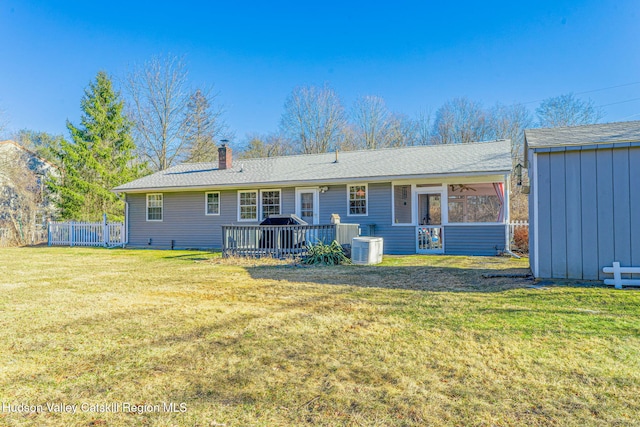 rear view of house featuring fence, a lawn, cooling unit, a chimney, and a sunroom