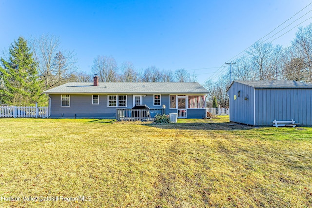 back of house with a yard, an outdoor structure, a chimney, and fence