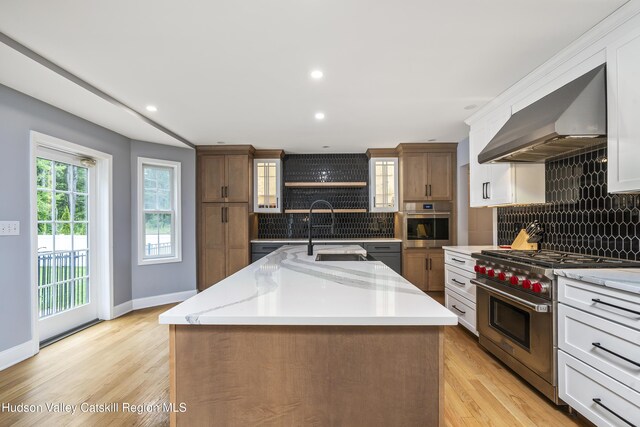 16 Shinnecock Hills Dr, Colonie, NY 12205 - kitchen featuring stainless steel appliances, exhaust hood, a sink, tasteful backsplash, and a kitchen island with sink
