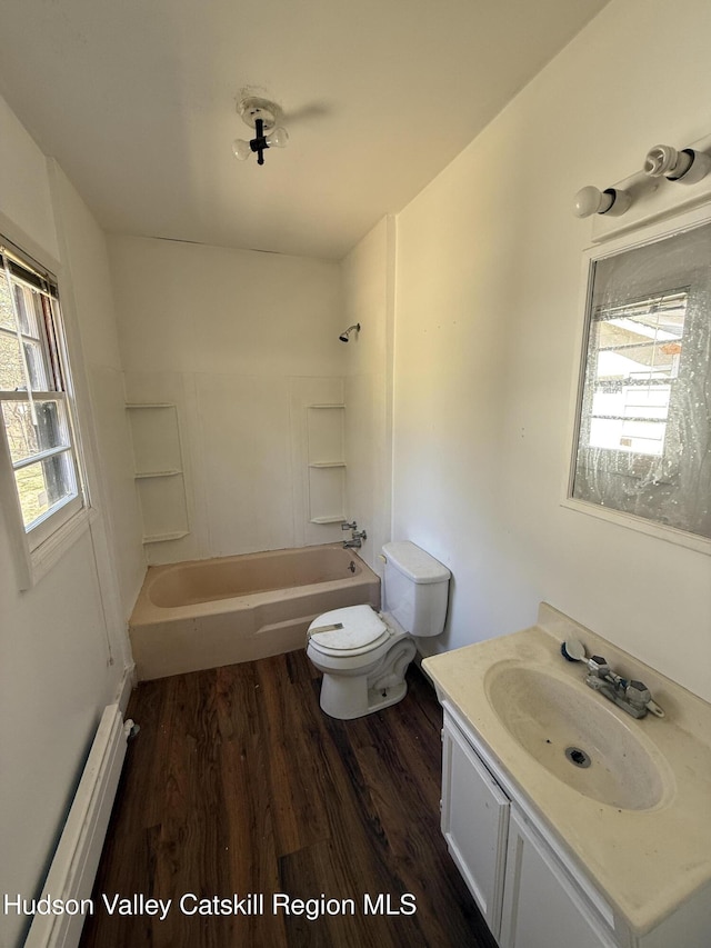 bathroom with toilet, wood finished floors, baseboard heating, vanity, and shower / bathtub combination