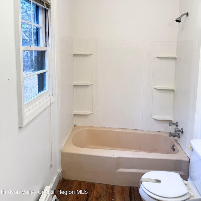 bathroom featuring a wealth of natural light, hardwood / wood-style floors, shower / bath combination, and toilet