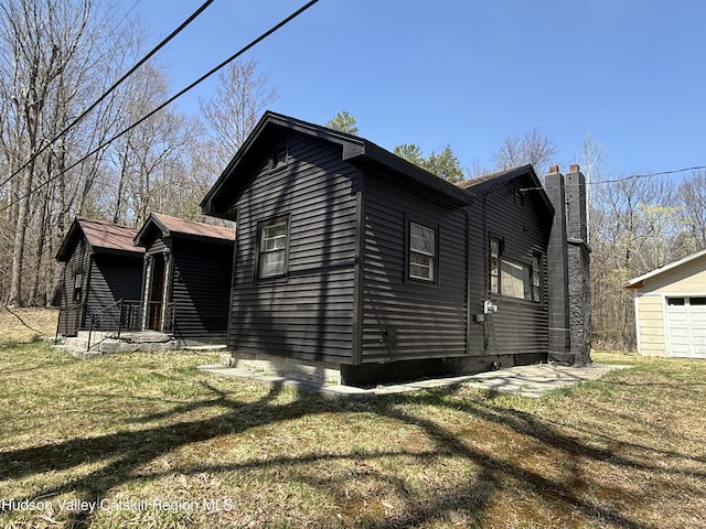 view of side of home featuring a yard, a chimney, and a garage