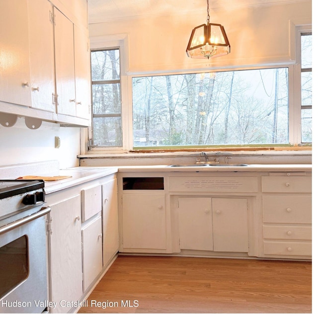 kitchen with sink, white cabinets, pendant lighting, and light wood-type flooring