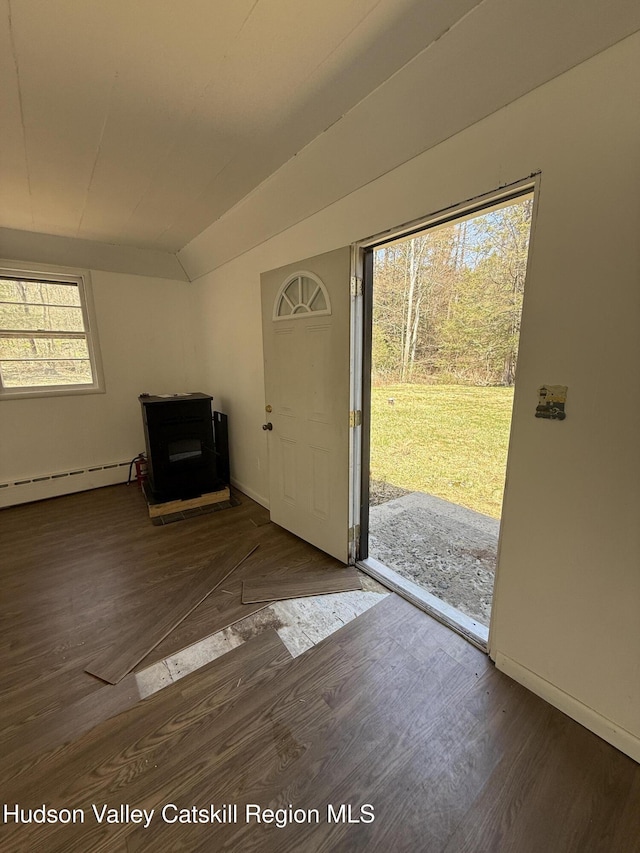 entryway featuring a wood stove, baseboards, baseboard heating, and wood finished floors