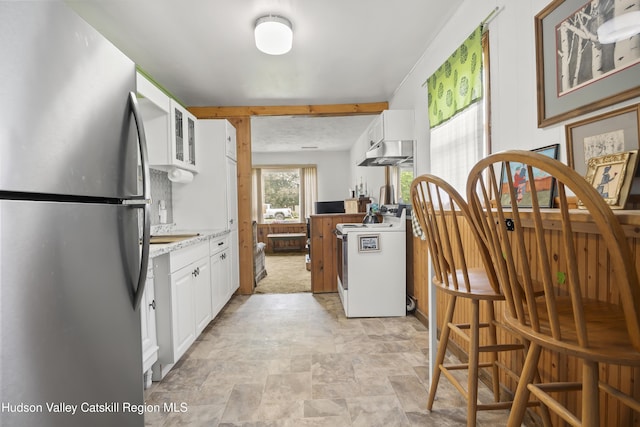 321 Lincoln Blvd, Hudson, NY 12534 - kitchen with freestanding refrigerator, white range oven, under cabinet range hood, white cabinets, and stone finish flooring