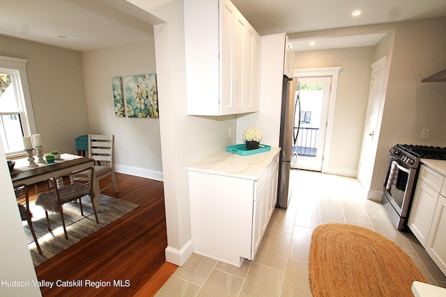 kitchen with white cabinets, stainless steel appliances, a wealth of natural light, and light hardwood / wood-style floors