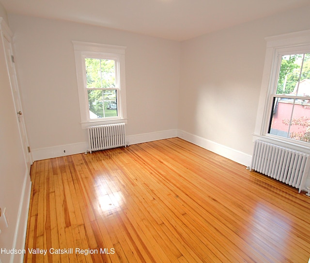 empty room featuring radiator heating unit and light wood-type flooring