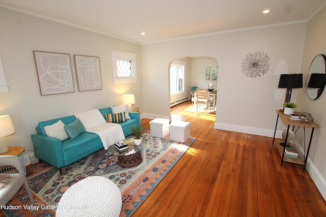 living room with a baseboard heating unit, hardwood / wood-style flooring, and crown molding