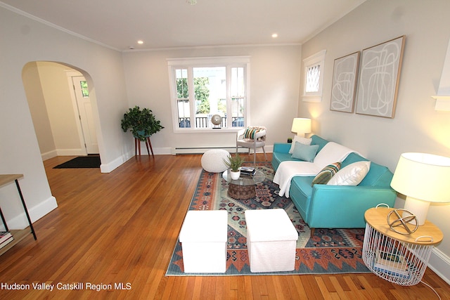 living room with wood-type flooring, ornamental molding, and a baseboard heating unit