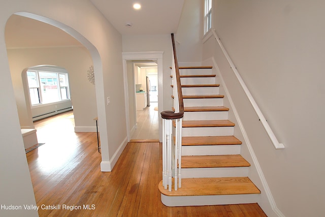 staircase with wood-type flooring and a baseboard heating unit