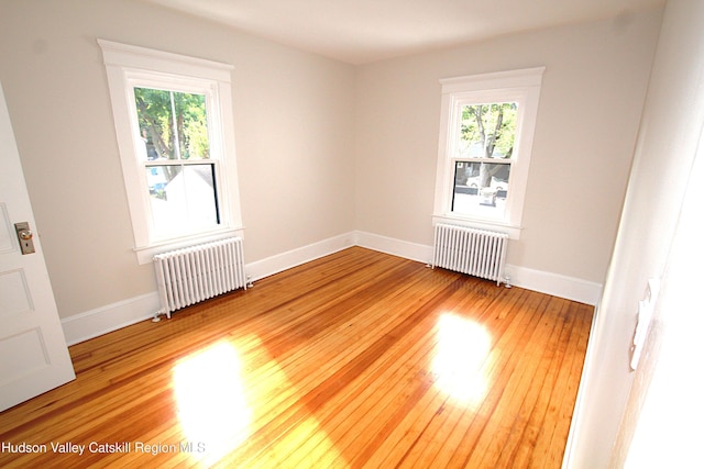 spare room with radiator, a wealth of natural light, and hardwood / wood-style flooring