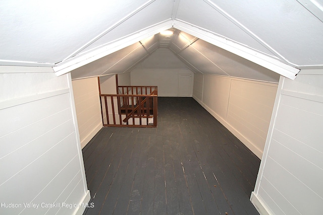 additional living space featuring vaulted ceiling and dark wood-type flooring