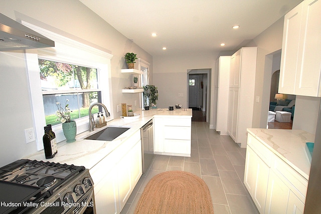 kitchen featuring kitchen peninsula, white cabinets, light stone countertops, and sink