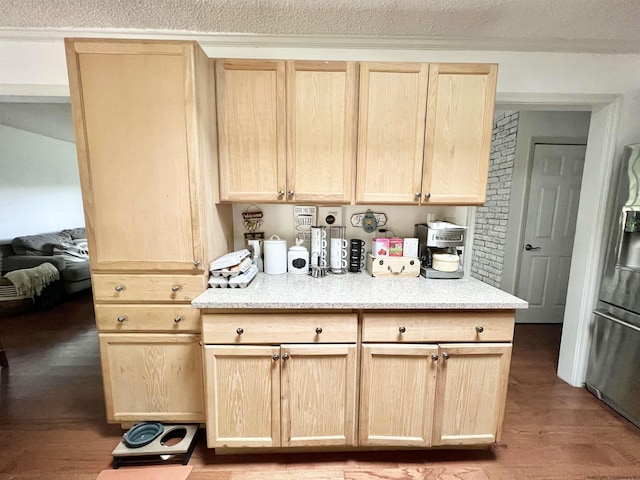 kitchen featuring light brown cabinets, light stone counters, wood finished floors, stainless steel fridge, and a textured ceiling