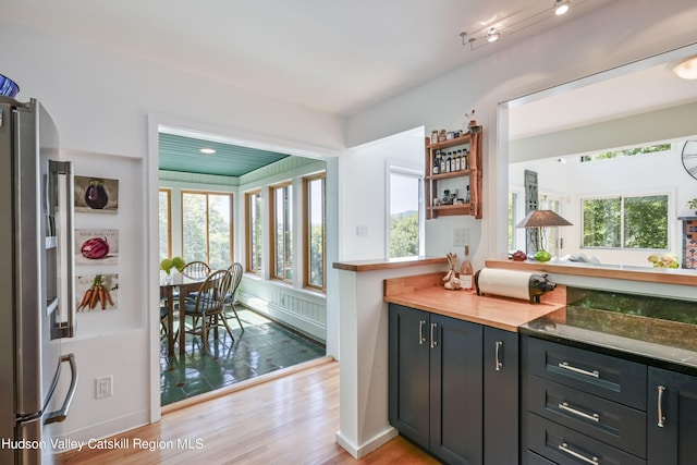 kitchen with stainless steel refrigerator, a wealth of natural light, and light hardwood / wood-style flooring