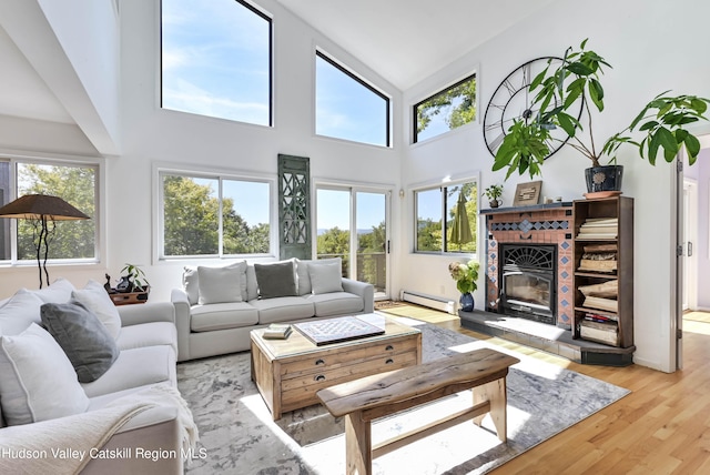 living room with light hardwood / wood-style floors, baseboard heating, and high vaulted ceiling