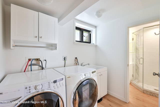 clothes washing area with separate washer and dryer, sink, cabinets, and light hardwood / wood-style floors