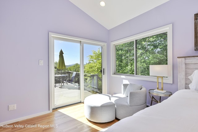 bedroom with access to outside, light hardwood / wood-style flooring, multiple windows, and lofted ceiling