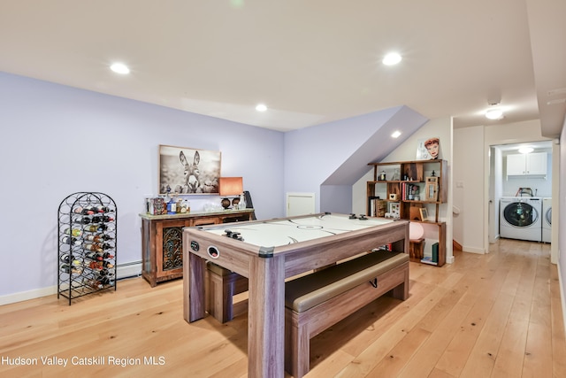 recreation room featuring light hardwood / wood-style flooring, baseboard heating, and washing machine and clothes dryer