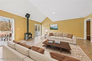172 Shields Rd, Red Hook, NY 12571 - living room featuring a wood stove, tile patterned floors, and vaulted ceiling