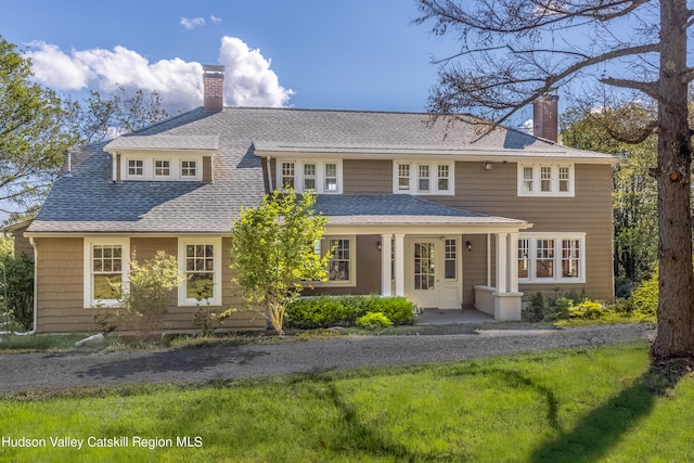 view of front of property featuring a chimney, a shingled roof, and covered porch