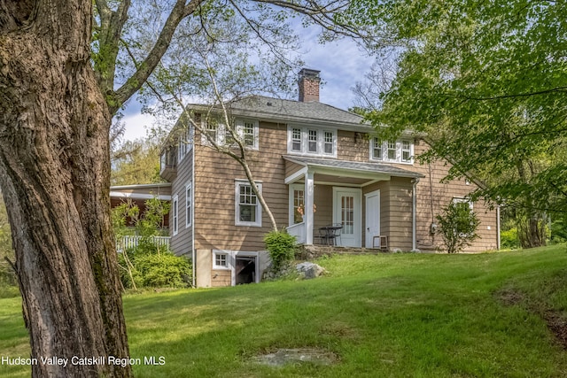 rear view of house featuring a yard and a chimney