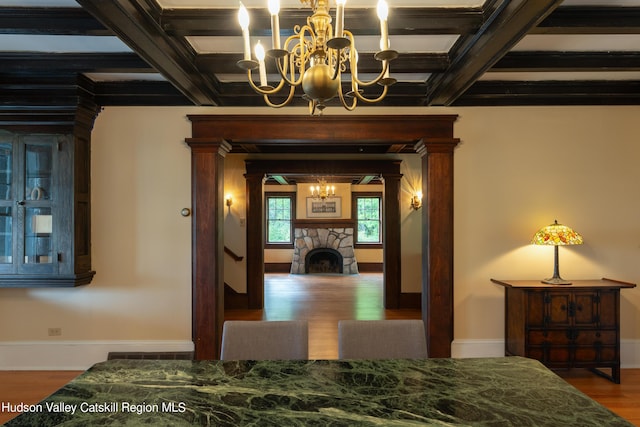 interior space featuring coffered ceiling, beam ceiling, a notable chandelier, and wood finished floors