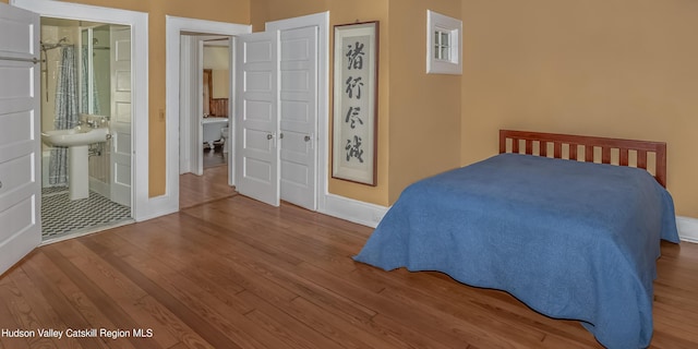 bedroom featuring baseboards, a sink, connected bathroom, and wood finished floors