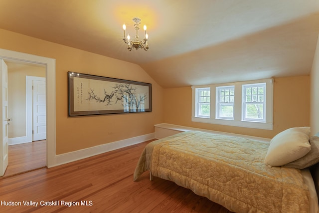 bedroom with lofted ceiling, baseboards, an inviting chandelier, and wood finished floors