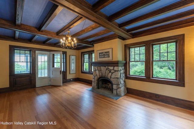 unfurnished living room featuring a notable chandelier, baseboards, beamed ceiling, coffered ceiling, and wood finished floors