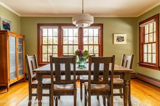 dining space featuring crown molding, a baseboard heating unit, and light wood-type flooring