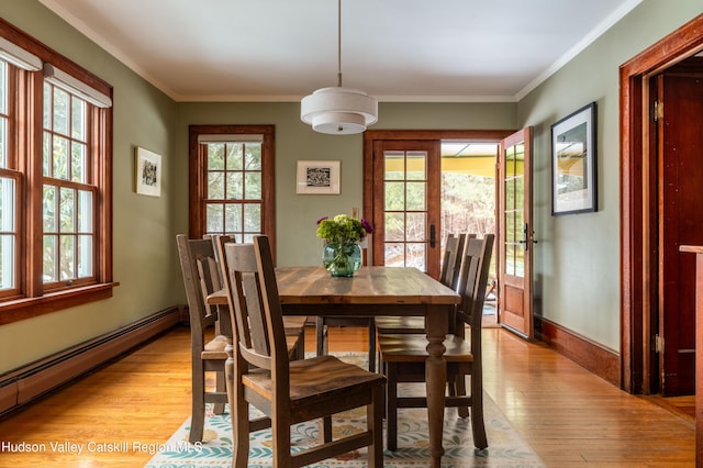 dining room with a baseboard heating unit, ornamental molding, and light wood-type flooring