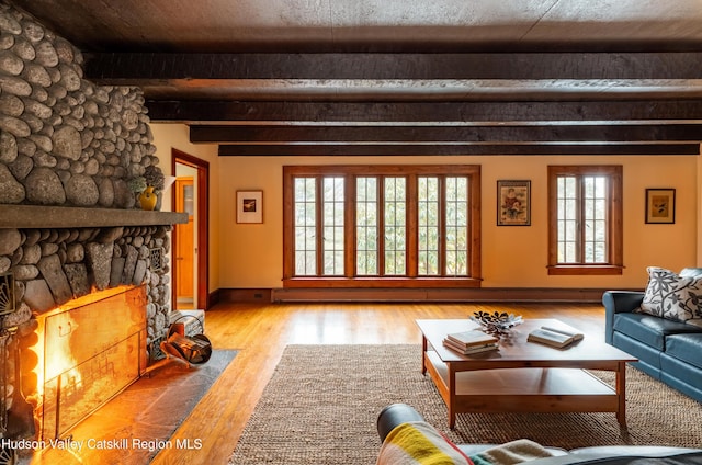 unfurnished living room featuring a fireplace, light hardwood / wood-style floors, and beamed ceiling