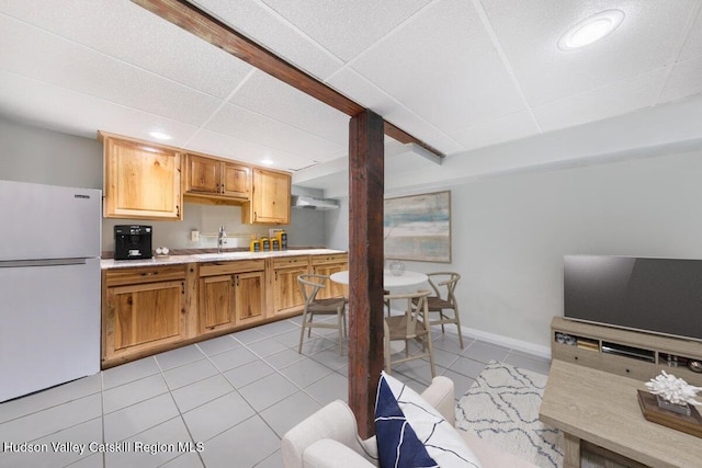 kitchen featuring a paneled ceiling, white fridge, light tile patterned floors, and sink