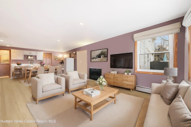 living room with baseboard heating and light hardwood / wood-style flooring