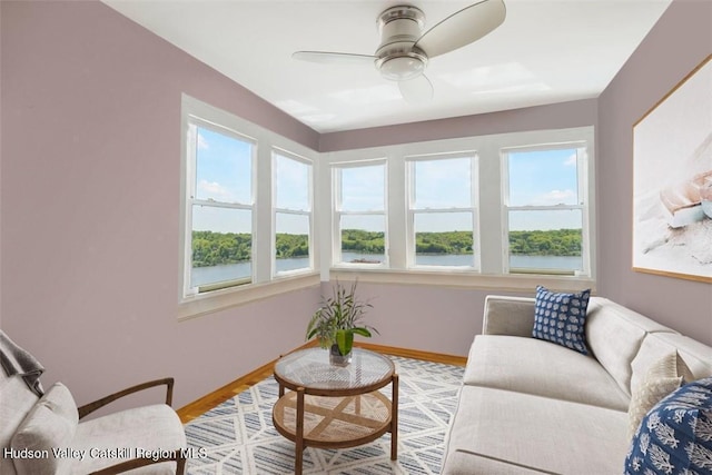 sunroom with ceiling fan and a water view