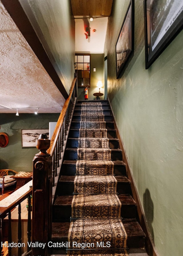 staircase with a textured ceiling and rail lighting