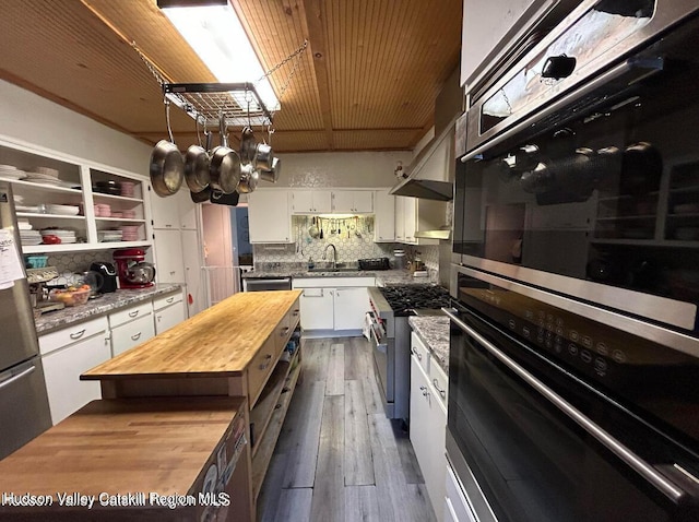 kitchen featuring dark wood-type flooring, decorative backsplash, white cabinetry, butcher block counters, and stainless steel appliances