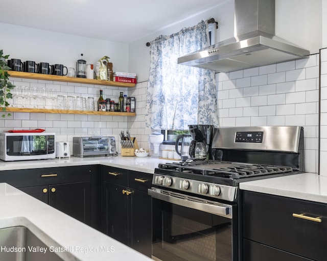 20 Sutton Hollow Rd, Windham, NY 12496 - kitchen featuring wall chimney range hood, stainless steel gas stove, white microwave, dark cabinetry, and decorative backsplash