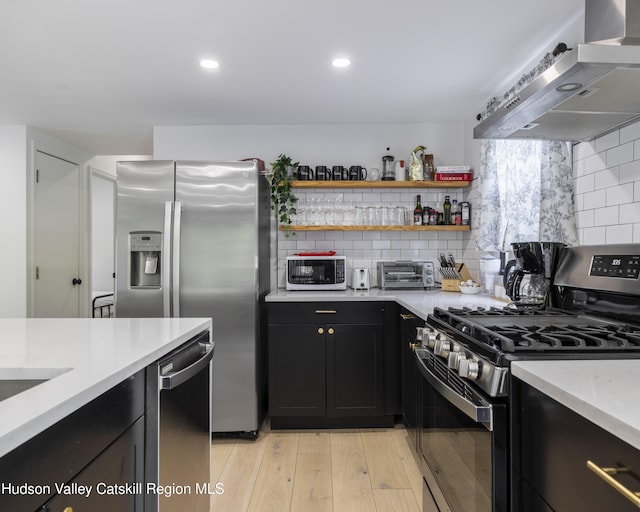 20 Sutton Hollow Rd, Windham, NY 12496 - kitchen with stainless steel appliances, ventilation hood, light countertops, dark cabinetry, and decorative backsplash