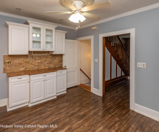 kitchen featuring white cabinetry, ceiling fan, dark hardwood / wood-style floors, crown molding, and dark stone counters