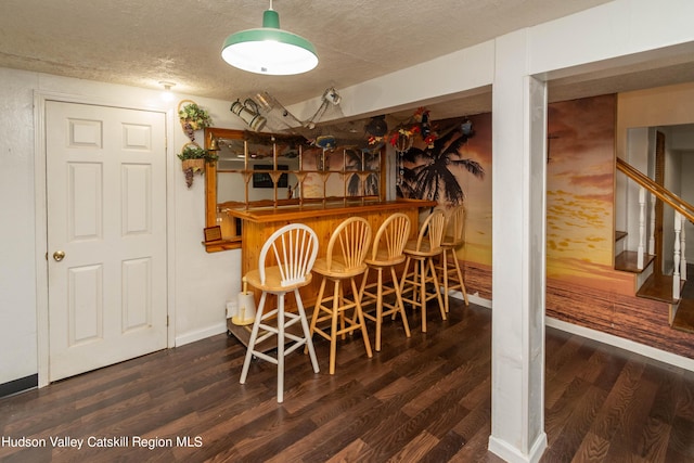 dining space featuring a textured ceiling, bar, and dark hardwood / wood-style floors