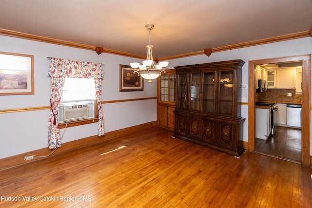 unfurnished dining area featuring cooling unit, wood-type flooring, ornamental molding, and an inviting chandelier