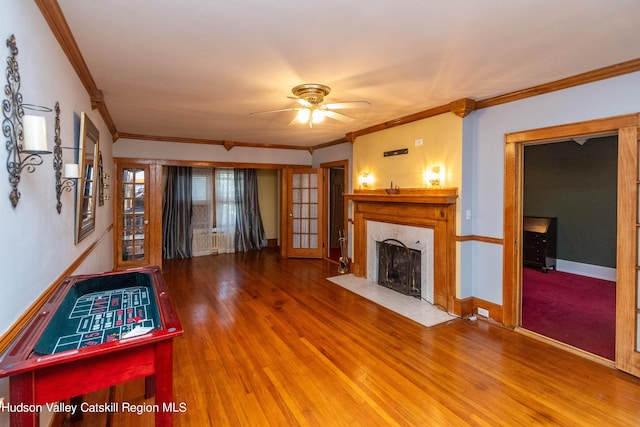 unfurnished living room with hardwood / wood-style flooring, ceiling fan, ornamental molding, and a fireplace