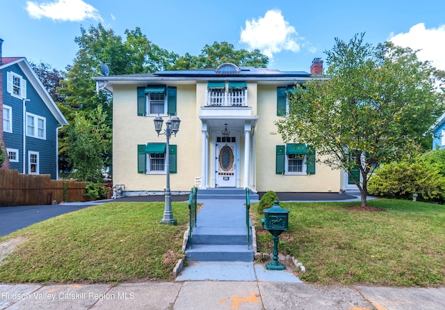 view of front of house with a balcony and a front yard