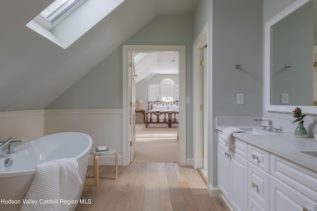 196 Wellington Ln, Cooperstown, NY 13326 - full bath featuring vaulted ceiling, hardwood / wood-style floors, a freestanding bath, double vanity, and a skylight