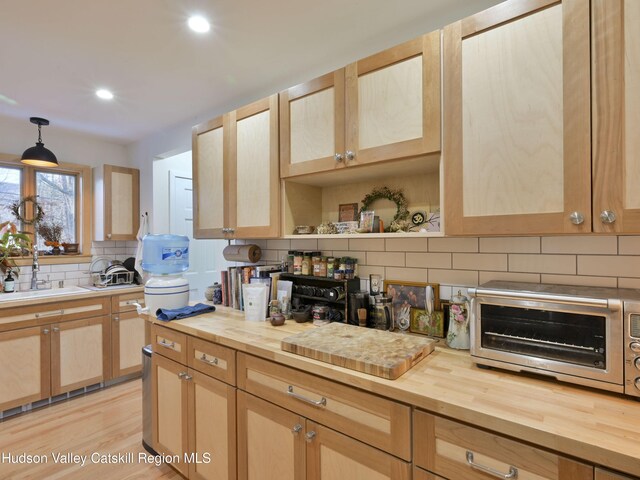 kitchen with decorative light fixtures, light brown cabinets, light hardwood / wood-style flooring, and wooden counters