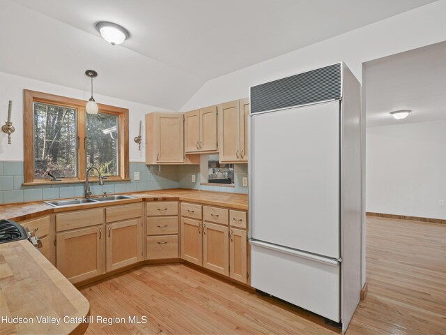 kitchen featuring sink, paneled fridge, decorative light fixtures, decorative backsplash, and light brown cabinetry