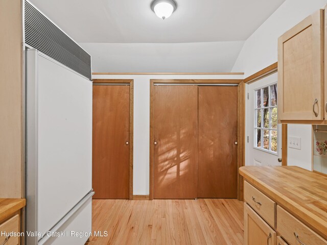 kitchen featuring lofted ceiling, light hardwood / wood-style flooring, paneled refrigerator, and light brown cabinets